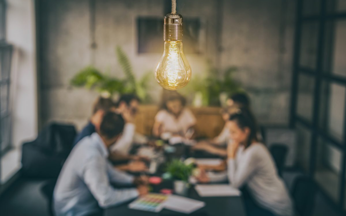 People gathered around a table under a hanging light bulb