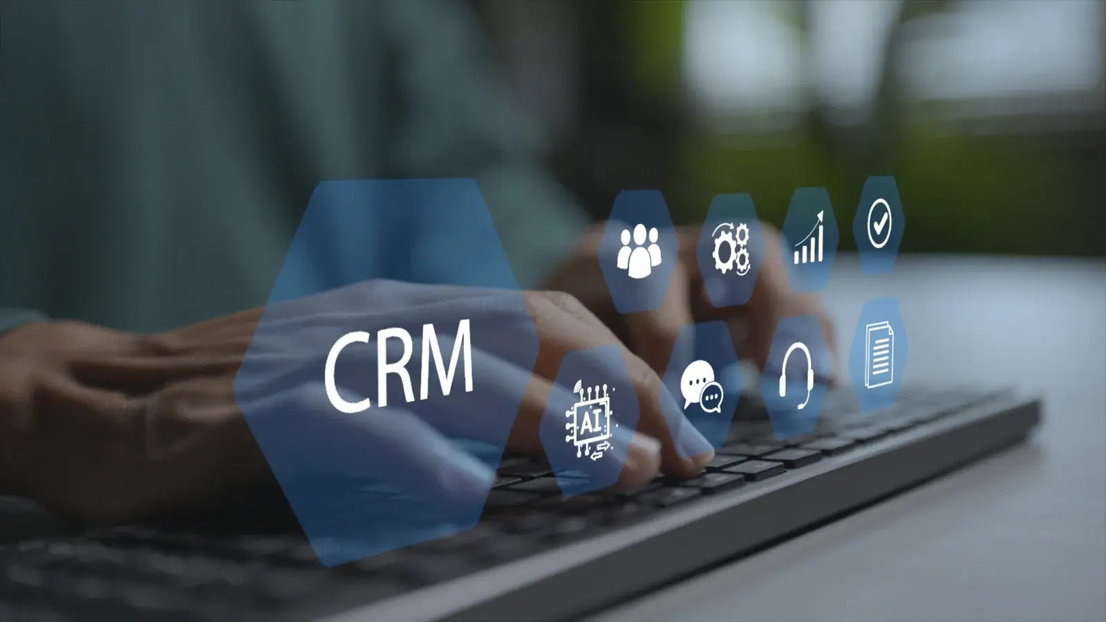 Hands at a keyboard with CRM and customer-management symbols.